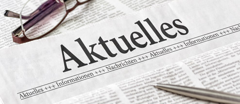 Brille und Stift auf einer Zeitung, die Aktuelles berichtet